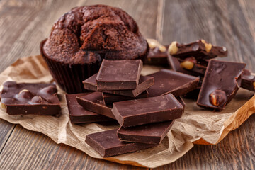 Chocolate cupcake with icing and chocolate bar in Dark lighting,Homemade delicious chocolate muffin on wooden background close-up