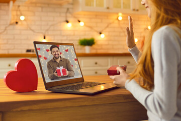 Young couple video calling each other during quarantine and showing Valentine gifts they prepared
