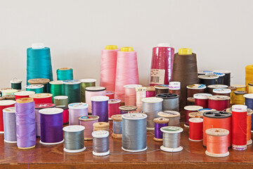 A large group of assorted bobbins with multicolored threads for sewing, needlework and tailoring.