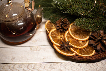 Fototapeta premium Christmas tea with dried orange in a basket with garland and fir branches and cones