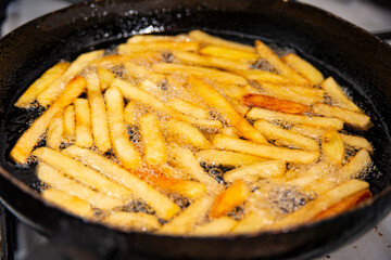 Fries almost finished in a skillet in oil.