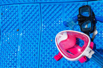 A full-face and traditional black mask for snorkeling and diving lies on the blue cover. Place for text. Pink for children and girls. Sea vacation concept. Copy space