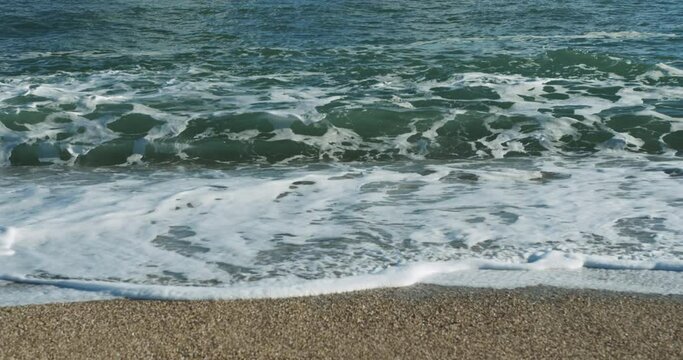 Waves crashing onto the beach on a sunny autumn day