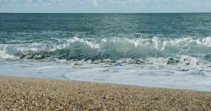 Waves crashing onto the beach on a sunny autumn day