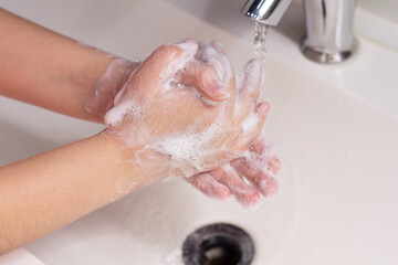 Washing hands with soap over a white sink