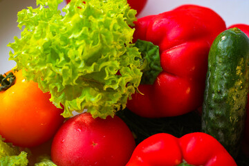Background from juicy ripe and tasty vegetables. Yellow and red tomatoes, red bell peppers, arugula, lettuce, cucumbers.