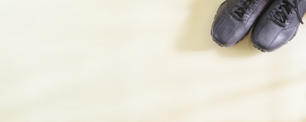 Pair of black shoes on long beige background with copy space