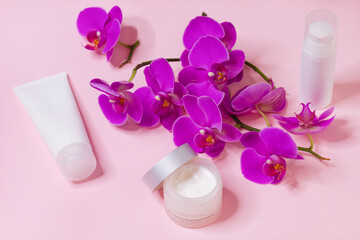 Obraz na płótnie Canvas Moisturizing cosmetics with orchid extract on pink background, beauty concept.