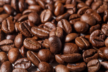 Naklejka premium Freshly roasted coffee beans background.Dark roasted coffee beans with scoop on wooden background.