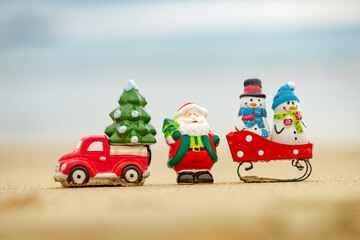 Toy Santa Claus against tropical ocean background. Christmas in hot vacation. Warm New Year climate, theme for posters, greeting cards.