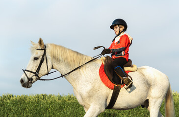 9 years boy in helmet ridding white horse