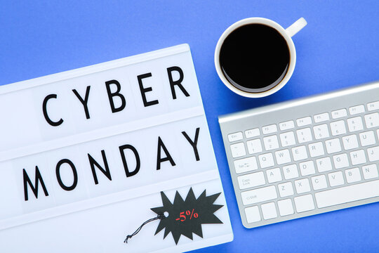 Lightbox with inscription Cyber Monday, cup of coffee and keyboard on blue background