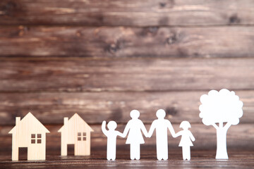 Paper family figures with tree and houses on brown background