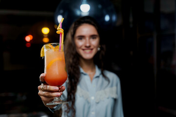 Girl with cocktail is drinking in night club before party. Advert for bar and night clubs. Citrus alcohol drink with orange juice