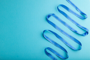 Blue ribbon on a blue pastel background. Top view, copy space.