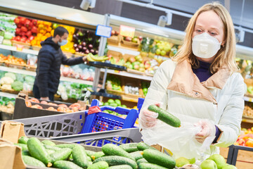 woman in mask and protective gloves buying food in shop at coronavirus epidemic