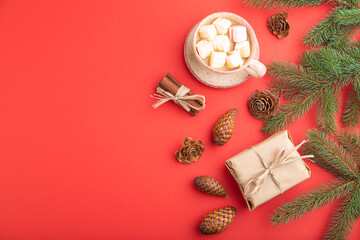 Christmas or New Year composition. Decorations, cones, fir and spruce branches, cup of coffee, on a red background. Top view, copy space.