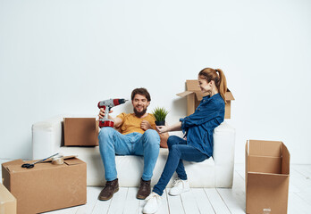 Fototapeta na wymiar cheerful man and woman on the couch moving interior cardboard boxes