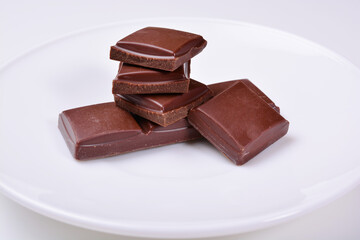 pyramid of pieces of dark chocolate on a white plate.