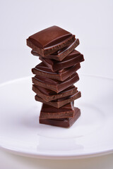 vertical pyramid of pieces of dark chocolate on a white plate.