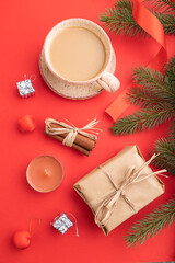 Christmas or New Year composition. Decorations, box, fir and spruce branches, cup of coffee, on a red background. Top view.