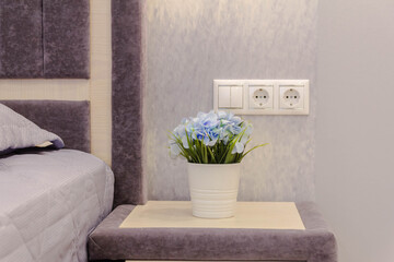 planters with a bouquet of flowers on the bedside table in a modern interior