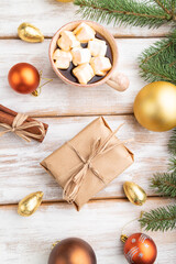 Christmas or New Year composition. Decorations, box, balls, fir and spruce branches, cup of coffee, on a white wooden background. Top view.