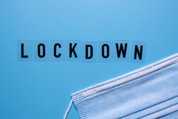 The word lockdown and a medical mask on a blue background. Second wave covid 19.