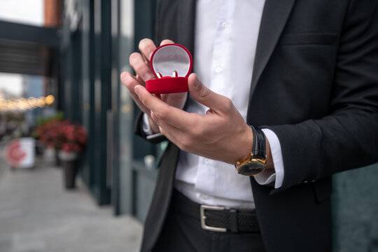 Close up picture of mans hands holding a box with engagement ring