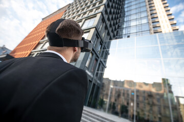 Man wearing a black suit in vr glasses looking at the building
