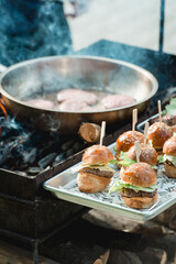 Chef making beef burgers outdoor on food festival event. Street food ready to serve on a food stall.