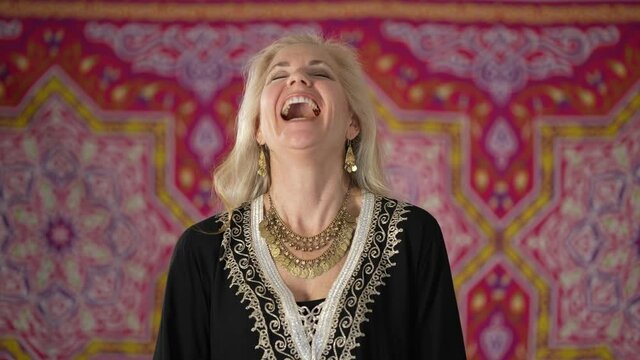 Portrait of a gorgeous blond haired ethnic woman laughing and smiling looking at camera. Happy mature woman enjoys life.
