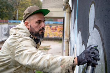 Graffiti artist in action, drawing on the wall with spray paint in a can. Street art culture concept.
