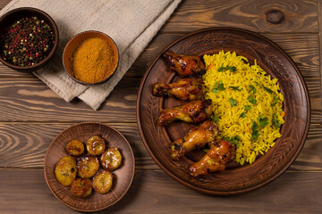 West African food. Rice with fried chicken and bananas, on a wooden background