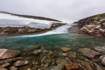Summer landscape with blue river and snow in norwegian tundra