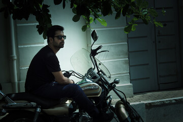 Puducherry, South India: An adult Indian male bike rider with beard in sunglasses on a motor bike /...