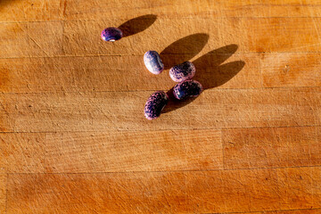 A few fresh heirloom scarlet runner beans on a light wooden cutting board