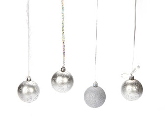 Closeup of four silver decorative Christmas balls hanging from a silver thread on a white background