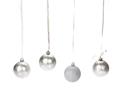 Closeup Of Four Silver Decorative Christmas Balls Hanging From A Silver Thread On A White Background