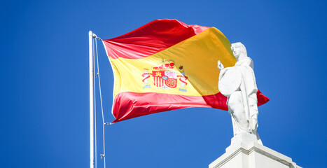 Coat of arms on the flag of Spain in the blue sky of Barcelona.