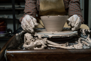 pottery, workshop, ceramics art concept - closeup on male hands sculpt new utensil with a tools and...