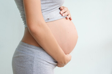 pregnant woman stands sideways and holds her belly. Pregnancy, childbirth, motherhood.