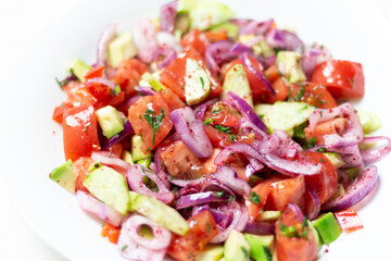 vegetable salad with  red onion, tomato, cucumber, avocado, dill, sumach, paprika, olive oil  in white bowl