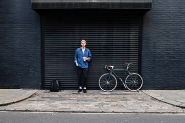 Professional Freelancer Young Man Standing With His Bike And Holding Coffee Outside.