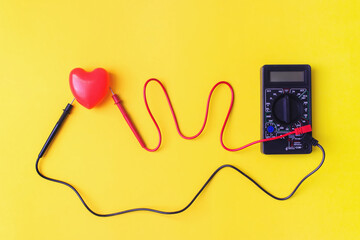 Digital multimeter with probes and red heart on a yellow background. Healthy Concept. Vital energy...