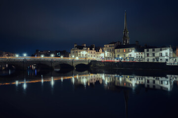 Fototapeta premium Night view of bridge over the River Ayr and embankment at the Ayr city. Street lamps light. Ayr, Scotland, United Kingdom