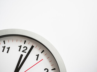 Close up of a ticking clock on white background, pointing a few minutes past midnight, copyspace