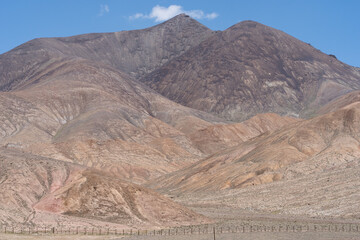 Rocky mountain peak with rugged slopes rising above an arid plain in the Pamir region of Tajikistan.