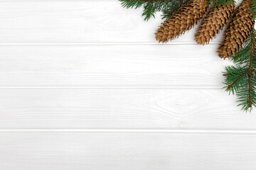 Fototapeta na wymiar Pine cones and branches on white wooden background. New Year poster