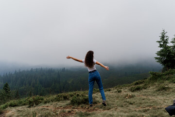 Girl is travelling in the mountains. Foggy day. Hiking and climbing up to the peak of the mountain....